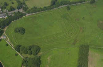 Oblique aerial view centred on the remains of the Roman Fort, chapel and burial ground, with road bridge adjacent, taken from the SE.