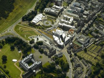 Oblique aerial view centred on the Scottish Parliament with the exhibition centre and palace adjacent, taken from the NE.
