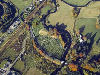 Oblique aerial view centred on the remains of the motte and bailey castle and the cemetery, taken from the SE.