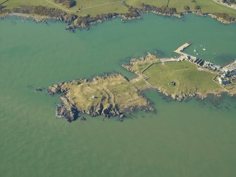 Oblique aerial view centred on the remains of the promontory fort and the chapel, taken from the ENE.