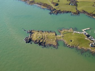 Oblique aerial view centred on the remains of the promontory fort and the chapel, taken from the NE.