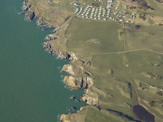 General oblique aerial view centred on the remains of the promontory forts, the anti-aircraft battery, buildings and huts, taken from the ESE.