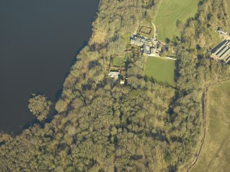 Oblique aerial view centred on the remains of the castle and crannog with the cottage and offices adjacent, taken from the SSE.