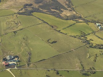 Oblique aerial view centred on the remains of the settlement with the farmsteading adjacent, taken from the E.