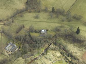 Oblique aerial view centred on the country house and stables and the remains of the church, taken from the W.