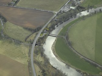 Oblique aerial view centred on the suspension bridge, farmhouse, farmsteading, cottage and road bridge, taken from the N.