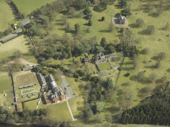 Oblique aerial view centred on the remains of the abbey with the hotel and country house adjacent, taken from the WNW.
