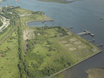 General oblique aerial view of the remains of the shipyard with the castle in the distance, taken from the NW.