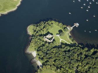 Oblique aerial view centred on the remains of the castle with the pier adjacent, taken from the W.