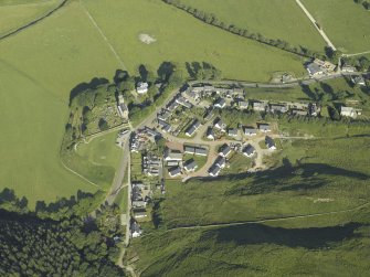General oblique aerial view of the village, centred on the church, churchyard, burial ground, museum and the remains of the cairn, taken from the ESE.