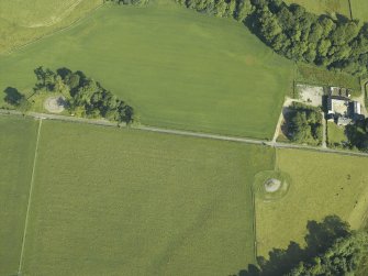 Oblique aerial view centred on the remains of the chambered cairn with the remains of the standing stone and stone circles and the farmstead adjacent, taken from the SE.