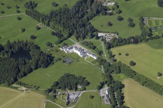 General oblique aerial view centred on the country house, bridge and gardens with the dairy, offices and church adjacent, taken from the S.