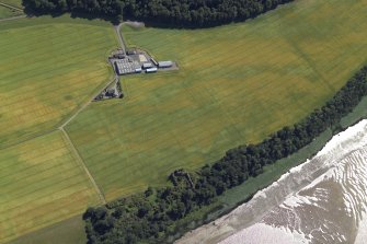 Oblique aerial view centred on the cropmarks of the enclosures and field boundaries with the farmhouse, farmsteading and remains of the castle adjacent, taken from the N.