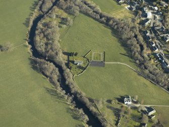 Oblique aerial view centred on the church, burial-ground, stables, farmsteading and manse, taken from the S.