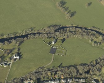Oblique aerial view centred on the church, burial-ground, stables, farmsteading and manse, taken from the ENE.