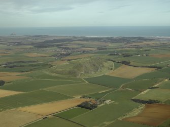 General oblique aerial view centred on the remains of the fort with the village in the distance, taken from the SW.