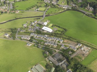 General oblique aerial view centred on the former railway station with the housing estate adjacent, taken from the WSW.