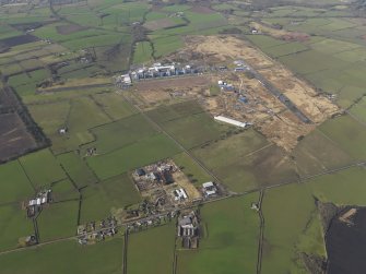 General oblique aerial view centred on the village with the Nuclear power station and airfield adjacent, taken from the ENE.