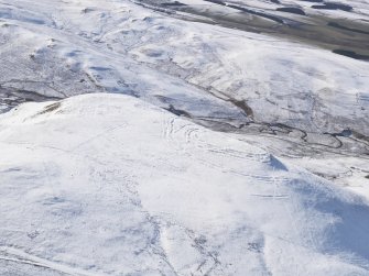 General oblique aerial view of Woden Law fort and linear earthworks in snow, looking SW.