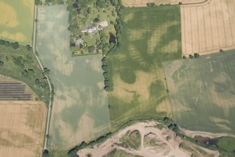 Oblique aerial view of the cropmarks of the rig, houses and pits with Woodhill House adjacent, looking NW.