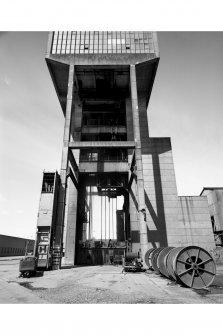 General view from S of No. 1 shaft winding tower, used to wind coal and men using two tower-mounted, geared, multi-rope A.C. friction winders with skip and counterweight, both manually controlled and equipped with dynamic breaking.  A spare skip can be seen to the left of the tower.