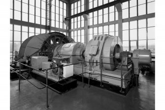 General view on top floor of no. 2 shaft tower showing the exciter from right to left, electric motor, gearbox and cable drum of the no. 2 winder.  This winder is equipped with one large cage and a counterweight on wood guides, and can carry 130 men on two decks.