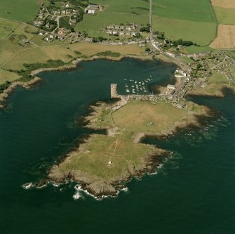 Oblique aerial view centred on the village, harbour, and the remains of the chapel and promontory fort, taken from the ESE.