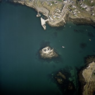 Oblique aerial view centred on the tower-house with the pier and town adjacent, taken from the S.