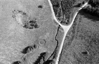 Oblique aerial view centred on the remains of the henge at Wormy Hillock, looking to the SE.