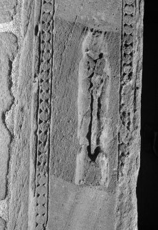 Detail of carved figure to left of doorway on W side of tower.