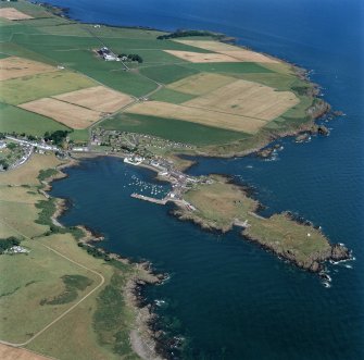 General oblique aerial view centred on the village, harbour, and the remains of the chapel and promontory fort, taken from the SSW.