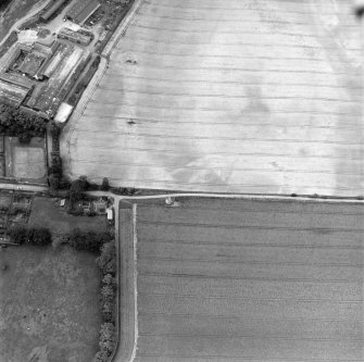 Phantassie, oblique aerial view, taken from the NE, centred on the cropmarks of an enclosure and a possible building. A dovecot is visible in the centre of the photograph and Phantassie farmsteading is shown in the top left-hand corner.