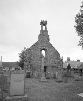 View from E showing the ruined gable, belfry and churchyard.