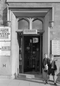 View of doorway and mouldings on W elevation, Town Hall, Market Square, Duns, showing road signs, advertisements and two schoolboys.