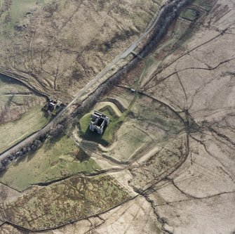 Oblique aerial view centred on the remains of the castle with chapel and moated site adjacent, taken from the NE.