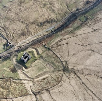 Oblique aerial view centred on the remains of the castle, chapel and moated site, taken from the NE.