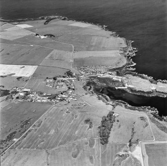 Oblique aerial view, taken from the WSW, centred on the village and harbour, and showing the remains of St. Ninian's Chapel in the centre right of the photograph.