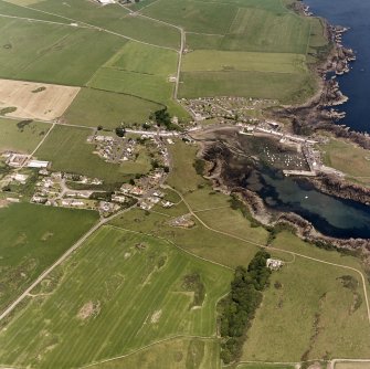 Oblique aerial view, taken from the SW, centred on the village and harbour. The remains of St. Ninian's Chapel are visible in the centre right of the photograph.