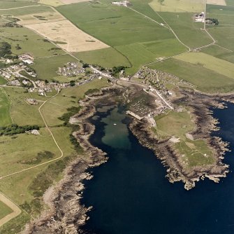 Oblique aerial view, taken from the S, centred on the village and harbour, and showing Isle Head fort and the remains of St. Ninian's Chapel in the bottom right-hand corner of the photograph.