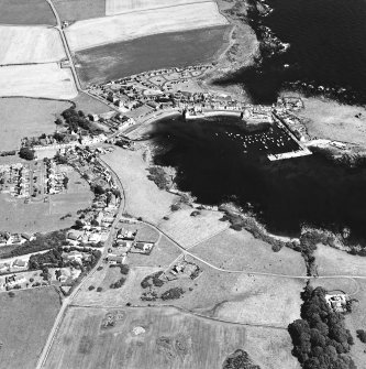 Oblique aerial view centred on the village and harbour with the remains of the chapel adjacent, taken from the SW.