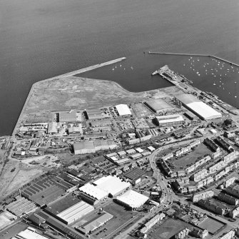 Oblique aerial view centred on the industrial estate with the office, works and harbour adjacent, taken from the SSW.