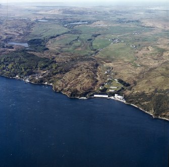 General oblique aerial view looking across the whisky distillery, pier, harbour and village towards the village of Keills and Loch Ballygrant, taken from the NE.
