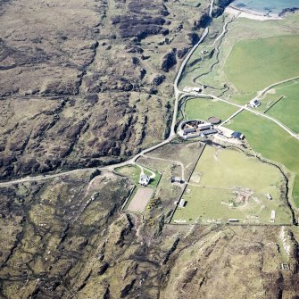 Oblique aerial view centred on the farmhouse, farmsteading, engine house and hut, taken from the NE.