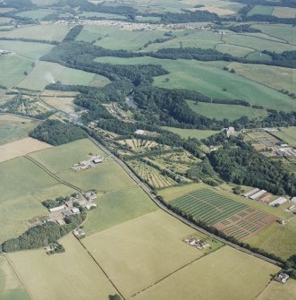 General oblique aerial view looking across the tower-house, school and agricultural college towards the village, taken from the NW.