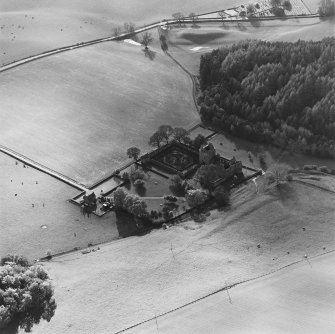 Oblique aerial view of Edzell Castle centred on the remains of the castle with motte-and-bailey castle, church and burial ground adjacent, taken from the NE.
