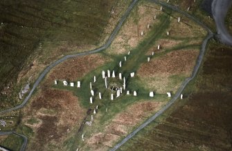 Oblique aerial view centred on the remains of the stone circle, stone alignments and chambered cairn, taken from the SSE.
