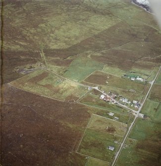 Oblique aerial view centred on the standing stone with the remains of the crofting township adjacent, taken from the ESE.