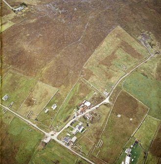 Oblique aerial view centred on the standing stone with the remains of the crofting township adjacent, taken from the NNE.