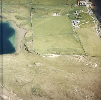 Oblique aerial view centred on the remains of the hut-circles, farmstead and rig with the hotel adjacent, taken from the WNW.