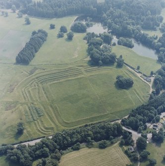 Oblique aerial view centred on the remains of the Roman Fort, chapel and burial ground, with road bridge adjacent, taken from the WNW.